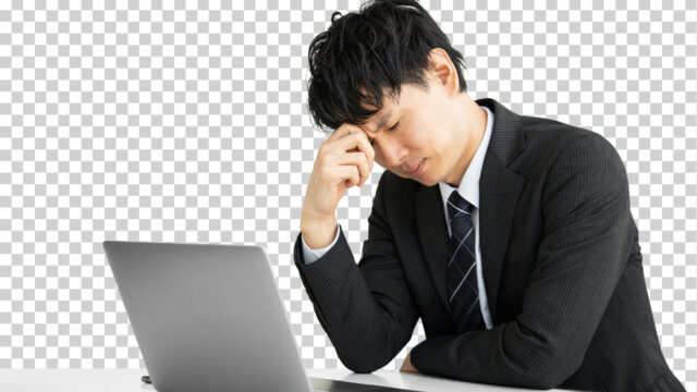 Businessman in a dark pinstripe suit at a laptop, head resting on his hand in apparent stress or fatigue at work.